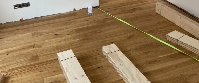 Dřevěná podlaha s materiály pro instalaci v parní místnosti.