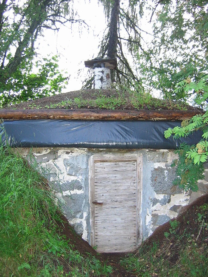 Hotový sklep z kamene s dřevěnými dveřmi ukrytý v kopci.