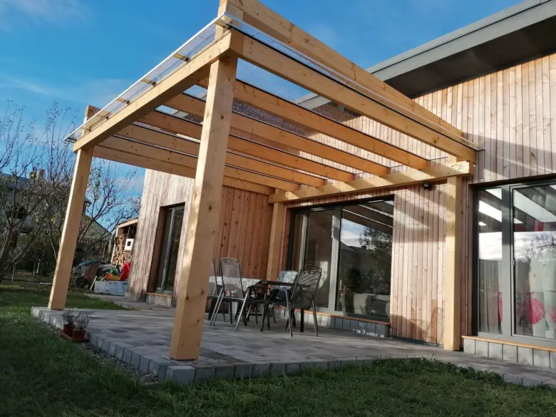 Dřevěná pergola s polykarbonátovou střechou na zahradním terasu.
