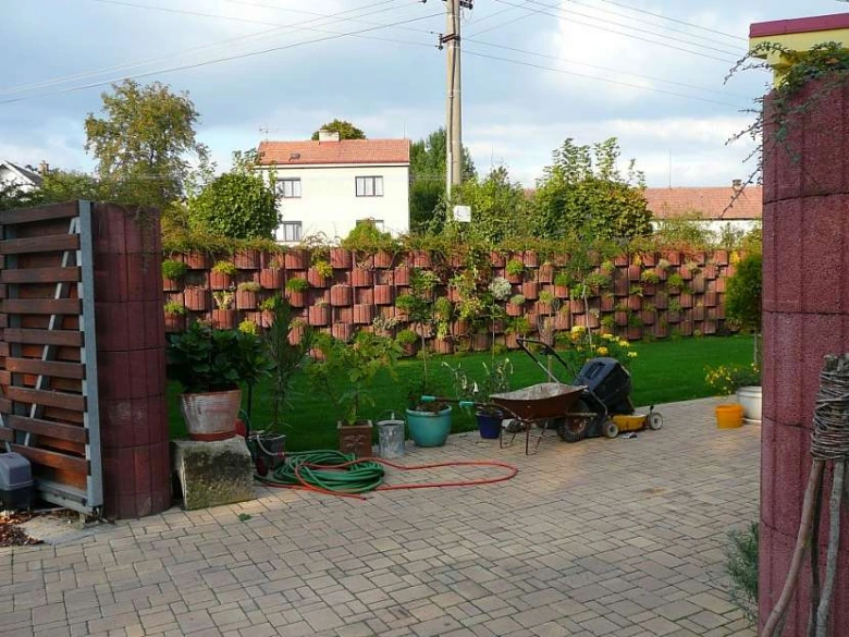Zelená zahrada s originálním zděným plotem plněním rostlin.