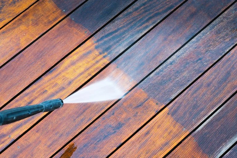Vysokotlaká voda čistí dřevěnou podlahu na balkóně a odstraňuje špínu.