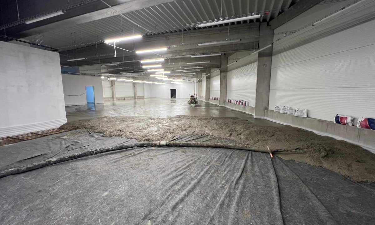 Práce na opravě betonové podlahy s nasypáváním písku.