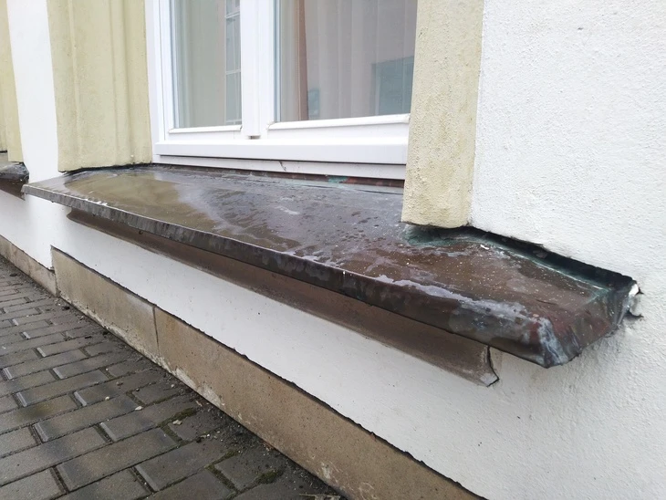 Starý okenní parapet s vlhkostí a průvanem poškozeným těsněním.