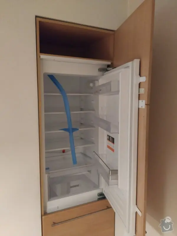 Vestavěná lednice v kuchyňském skříni během instalace.