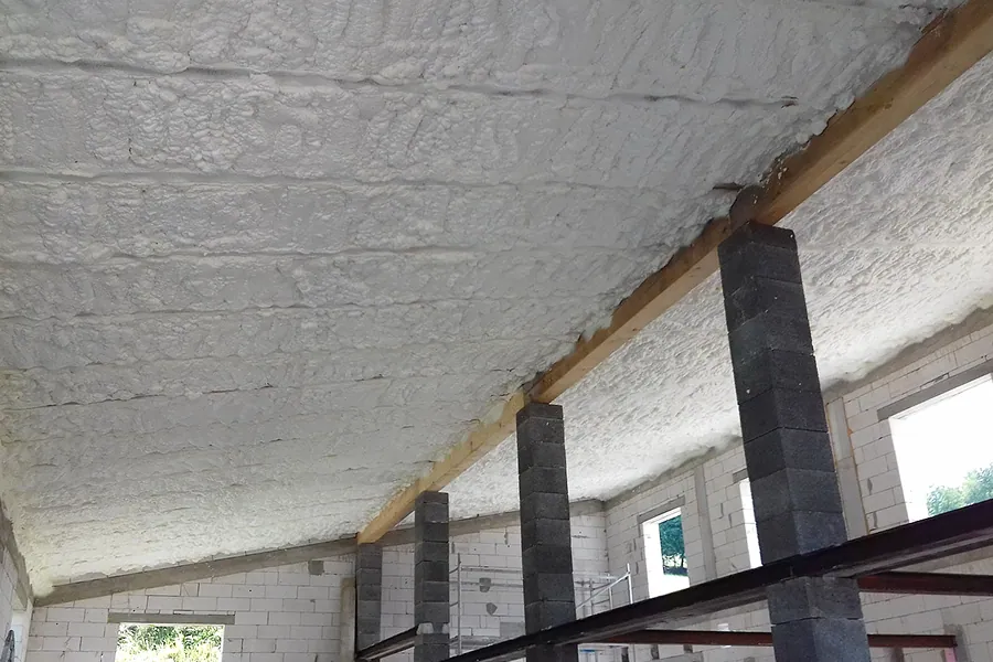 Bílá pěnová izolace stropu v garáži po aplikaci.