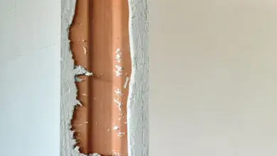Detail rohu sádrové omítky odhalující dřevěný profil za škrábající se vrstvou.