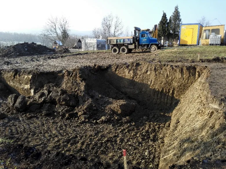 Výkop pro monolitický sklep s nákladním autem na staveništi.