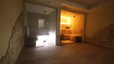 Interiér parní lázně s dřevěnou podlahou a kameny na stěnách.