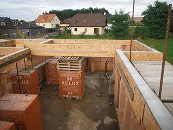 Neukončený dům s dřevěnými stěnami a příčkami během montáže.