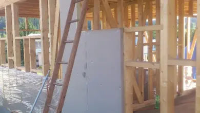 Stavba dřevěného rámu budovy s lezeckou žebříkem.