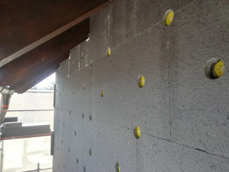 Polystyrenové desky připevněné ke zdi lepidlem s viditelnými žlutými bodovými spojnicemi