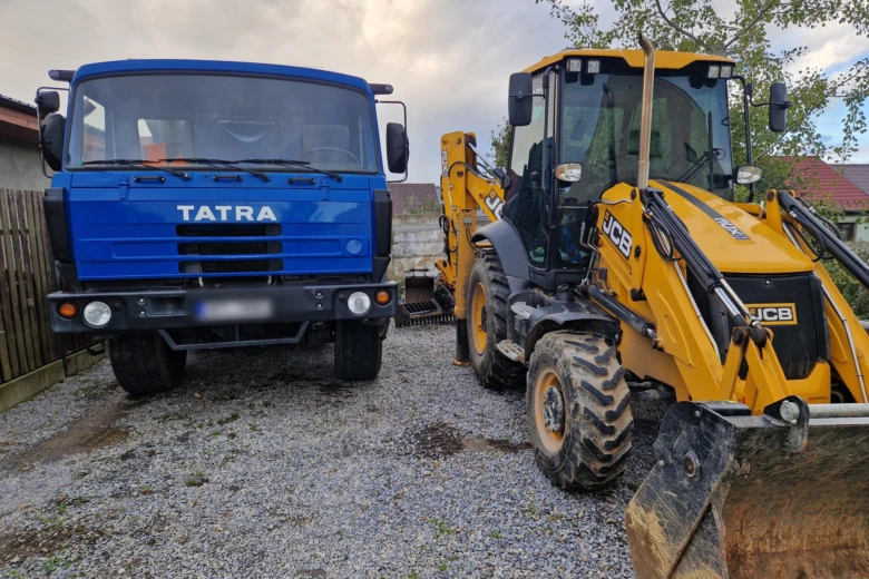 Modrý nákladní vůz Tatry a žlutá kopáčková technika pro zemní práce.