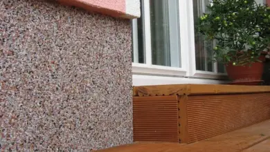 Detail spodní části domu s kamennou omítkou a dřevěným prahem.