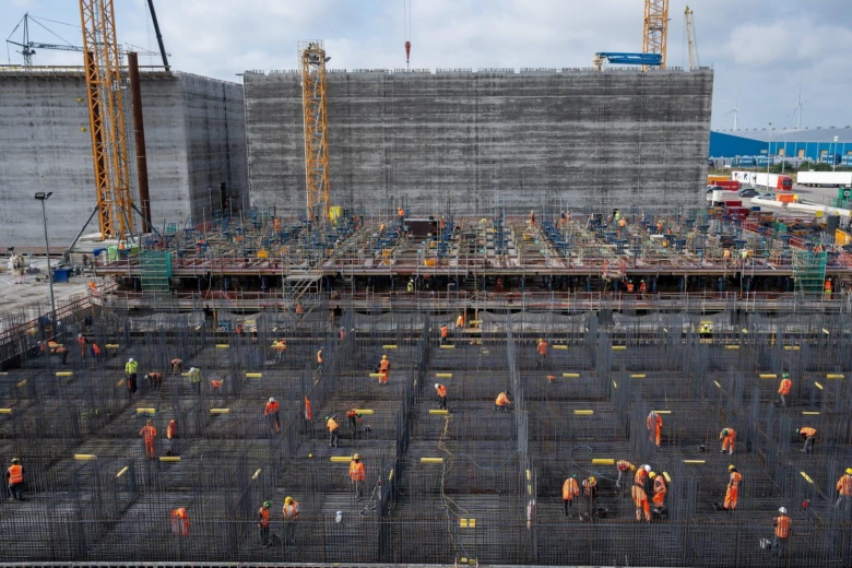 Pracovníci připravují betonovou základnu s ocelovým výztužným košem na staveništi.
