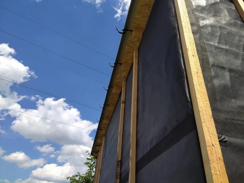 Střecha vany s dřevěným rámem a hydroizolací na modré obloze.