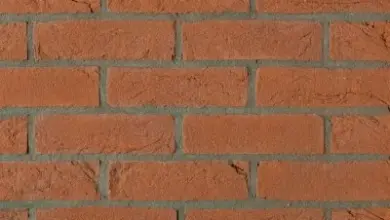 Detail červené cihlové zdi s viditelnými spárami.