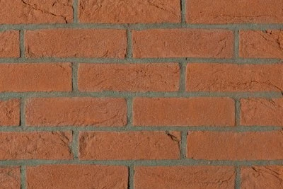 Detail červené cihlové zdi s viditelnými spárami.