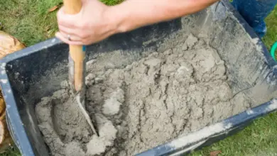 Míchání písku s cementem v vozíku na trávníku.