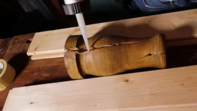 Náplňování praskliny ve dřevě bílým těsnícím materiálem.