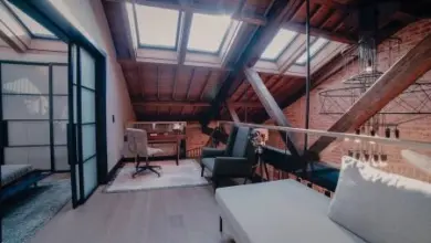 Moderní byt v podkroví s dřevěnými trámy a skleněným oddělením.