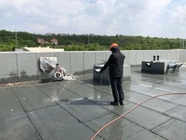 Muž opravuje plechovou střechu, která zatéká.