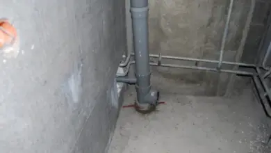 Šedá kanalizační stoupačka v betonu bez zvukové izolace.