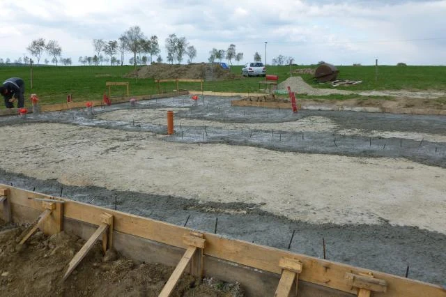 Zalévání betonu pro deskový základ domu na staveništi.