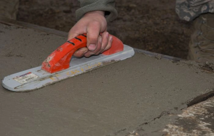 Ruka hladí čerstvý beton na poklopu ve sklepě
