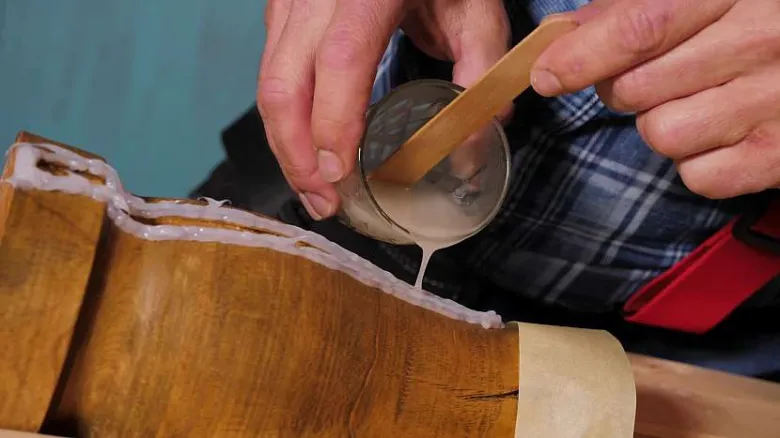 Stavitel utěsní prasklinu ve dřevě tekutým těsnicím materiálem.