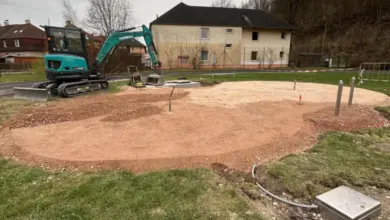 Zelený bagr pracuje na staveništi pro zemní práce.
