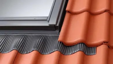 Detailní pohled na montáž šedého střešního lemování pod červenými taškami.