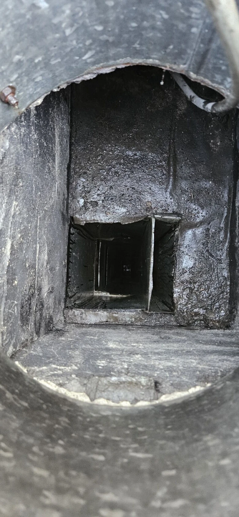 Vnitřek větrací šachty v panelovém domě s tmavými stěnami.