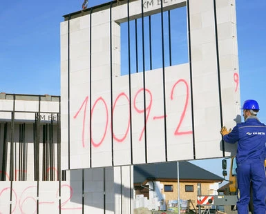 Montáž prefabrikované betonové stěny na stavbě s dělníkem.