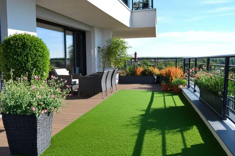 Moderní balkon s dřevěnou podlahou a umělým trávníkem.