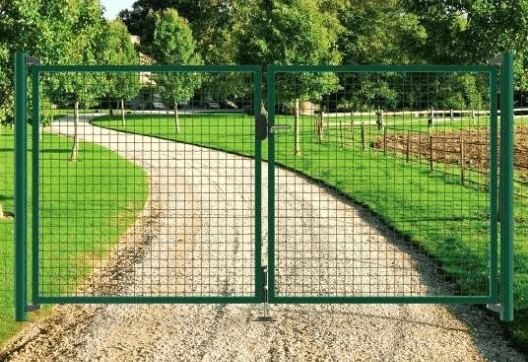 Zelená kovová brána na štěrkové cestě v zahradním prostředí.