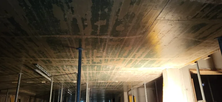 Mokrý betonový strop po dešti s viditelnými skvrnami.