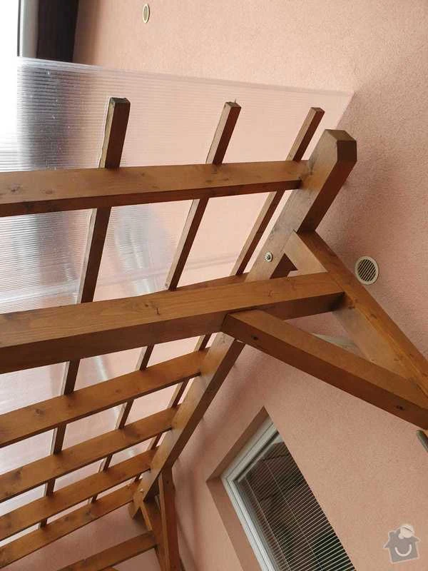 Montáž dřevěného přístřešku s viditelnými trámy a spoji.