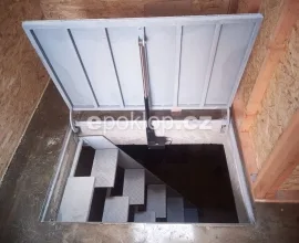 Otevřený sklepní poklop s přístupem na schodiště do podzemního prostoru.