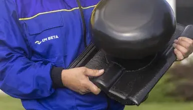 Montážní pracovník drží černou střešní kontralatě v rukou.