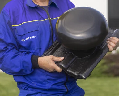 Montážní pracovník drží černou střešní kontralatě v rukou.