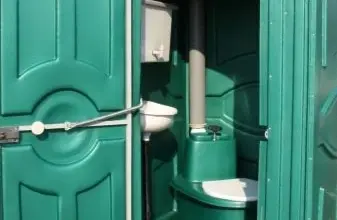 Zelená mobilní venkovní toaleta s otevřenou dveří.