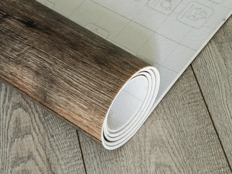 Rolovaný linoleum položený na dřevěnou podlahu jako základ.