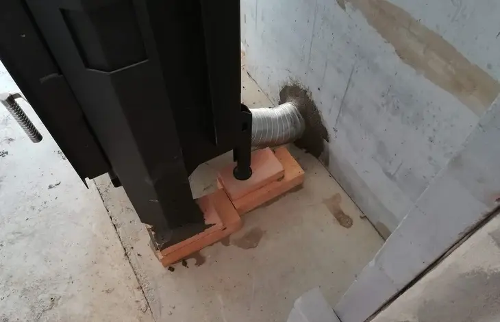 Flexibilní vzduchová hadice připojená ke zdi u krbu.