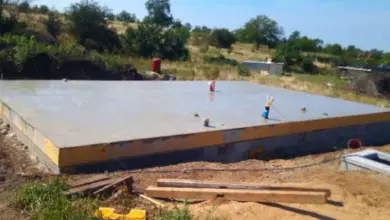 Čerstvě nalitá betonová podlaha na staveništi s dělníky.