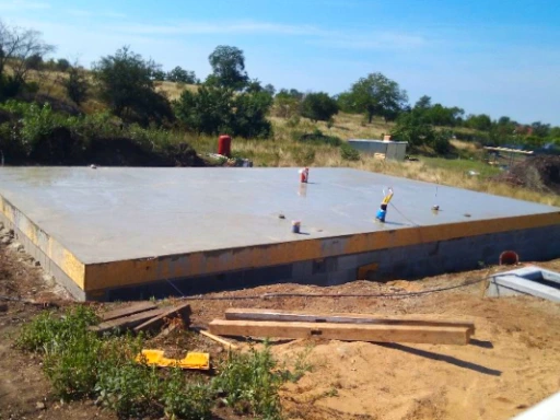 Čerstvě nalitá betonová podlaha na staveništi s dělníky.