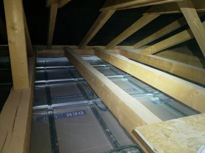 Instalace tepelné izolace mezi nosníky střešního trámoví.